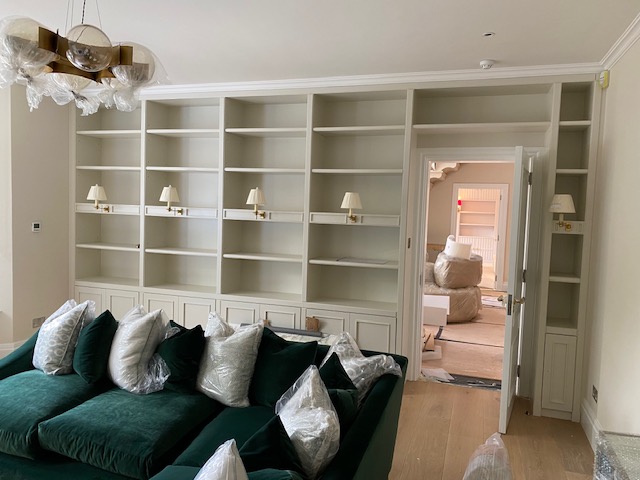 Sitting room with built-in shelving, sconces and a green velvet sofa
