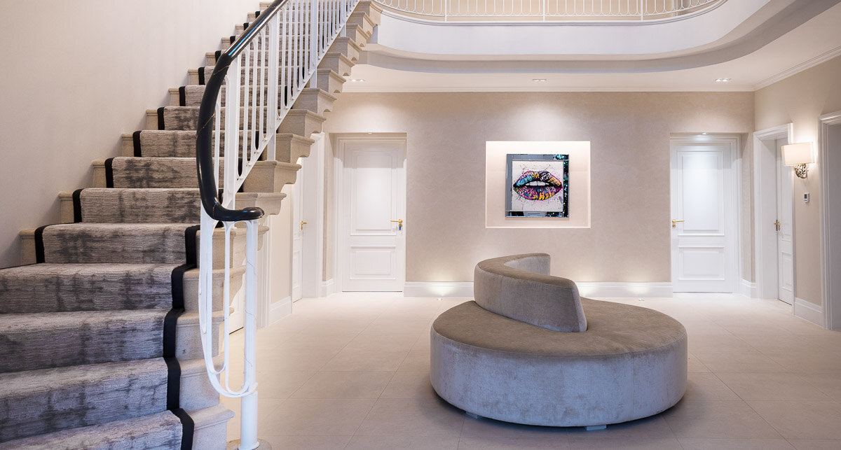 Entrance hall with curved staircase, circular settee and art niche