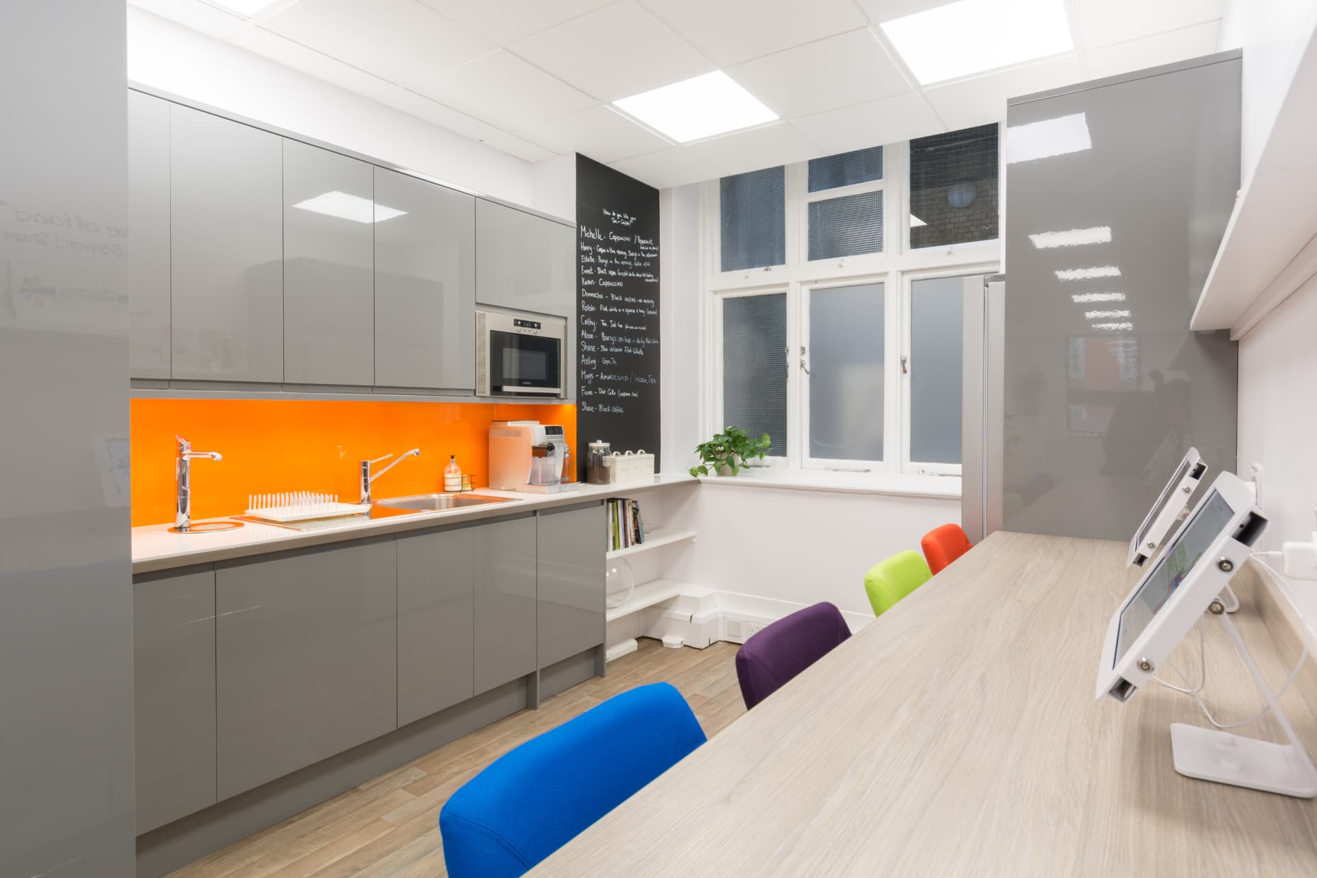 Breakout kitchen with orange glass splashback and honed grey cabinets