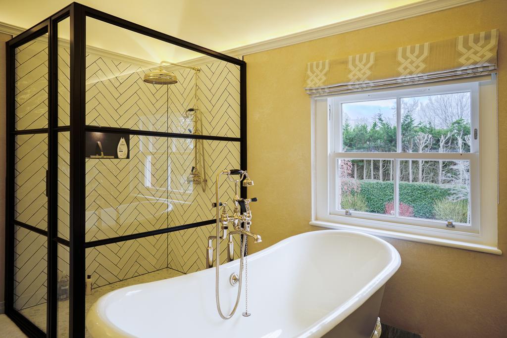 Bathroom with herringbone tiling, Crittall-style screen and freestanding bath