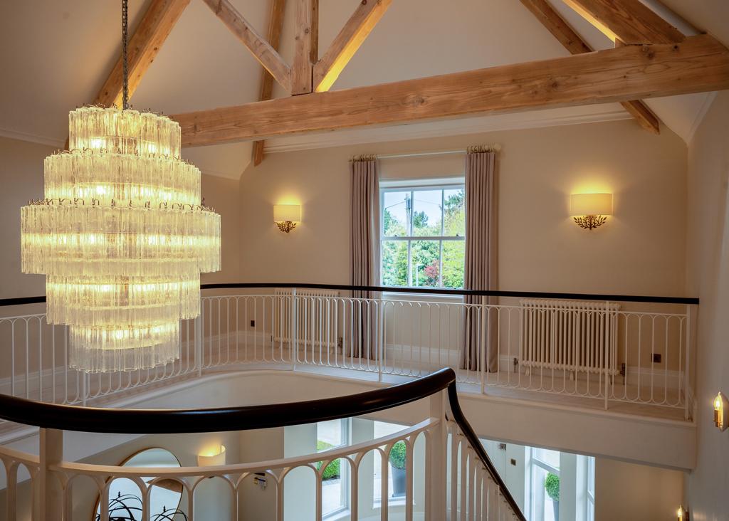 Double-height hall with exposed timber trusses and a chandelier