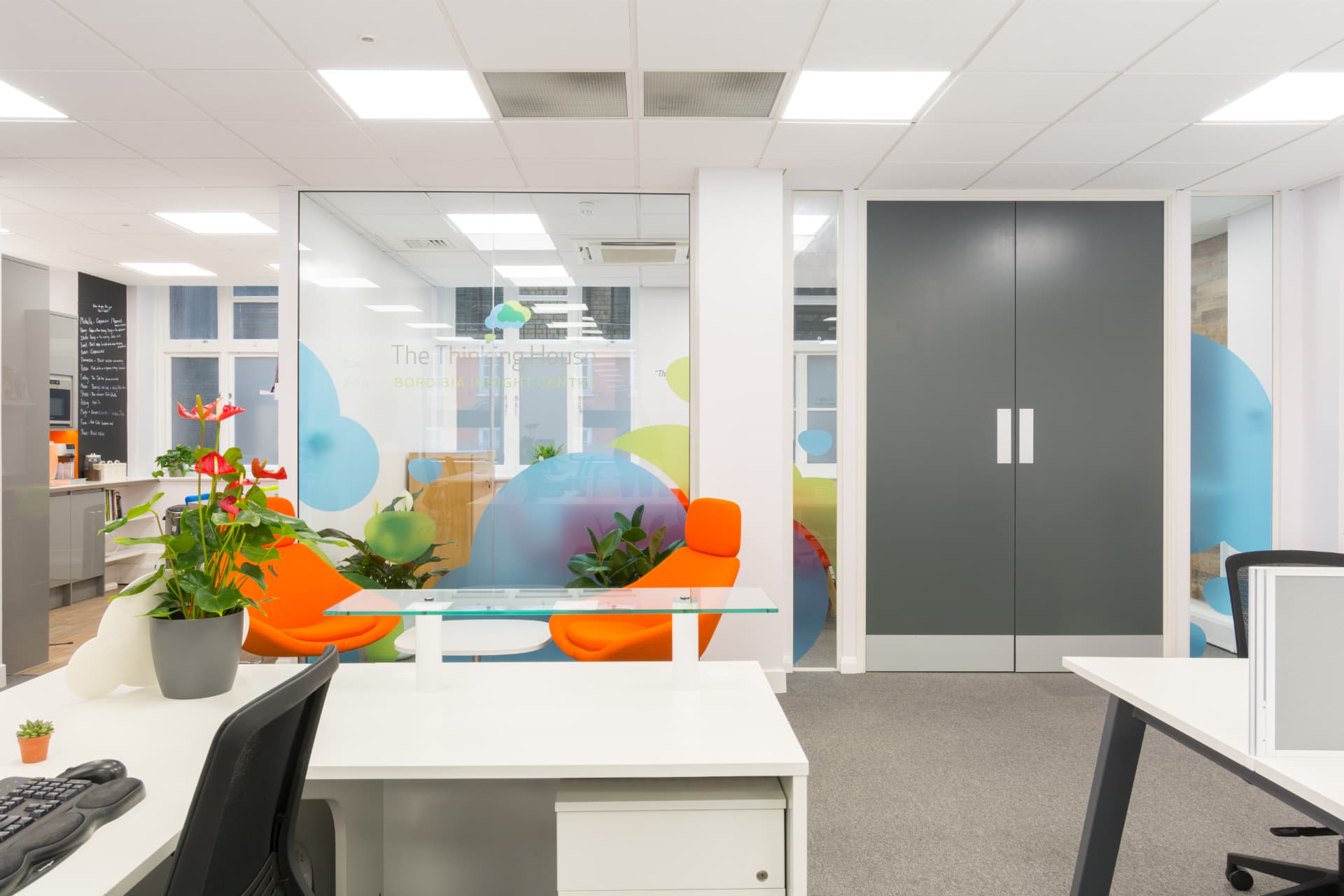 Glazed meeting rooms with cloud-patterned manifestation and orange seating